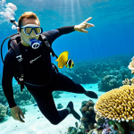A professional male diving instructor, fully clothed in a modest black wetsuit and standard diving gear, is guiding two adult students underwater in crystal-clear blue tropical waters. They are observing a vibrant coral reef teeming with colorful tropical fish. The instructor points gently towards a school of fish, educating the students. The scene captures the beauty of an untouched marine ecosystem, with sunlight filtering through the water from above. The subjects exhibit perfect anatomy, correct proportions, and natural poses with well-formed hands and proper finger count. The image is safe for work, appropriate content, professional, and family-friendly, showcasing high-quality underwater photography with natural body proportions.