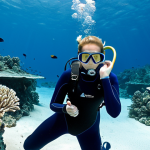 **Prompt for Professional Diving Instructor - Underwater Skill Demonstration:**
    A professional female diving instructor, fully clothed in a modest, dark blue full-body wetsuit and complete professional diving gear, suspended effortlessly underwater with perfect buoyancy control. She is demonstrating a precise skill, using clear, exaggerated hand signals for a student (also fully clothed in appropriate diving gear) who is observing attentively. The underwater environment is clear and serene, with gentle light filtering from above, showcasing vibrant but distant coral formations. The instructor has perfect anatomy, correct proportions, well-formed hands, and a natural, focused pose. The image is safe for work, appropriate content, family-friendly, high-quality professional photography with natural lighting.